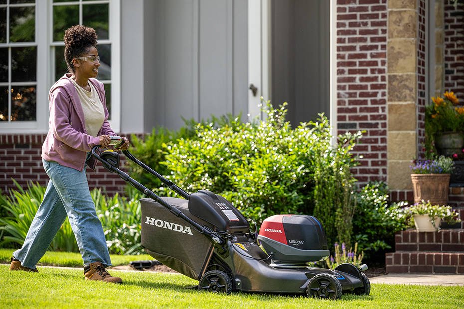 Woman using a Honda battery-powered lawn mower in a residential yard