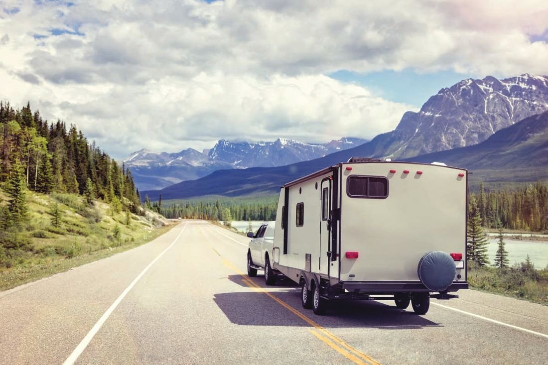 Pickup truck towing a travel trailer down a mountain highway