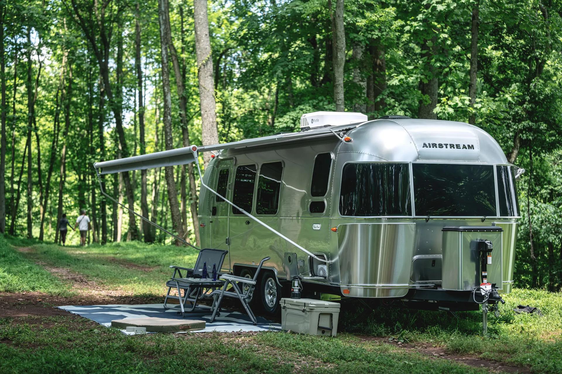 Airstream Flying Cloud with its awning out at a wooded campsite