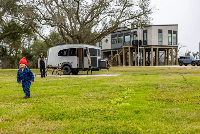 Family on the lawn beside an Airstream Basecamp