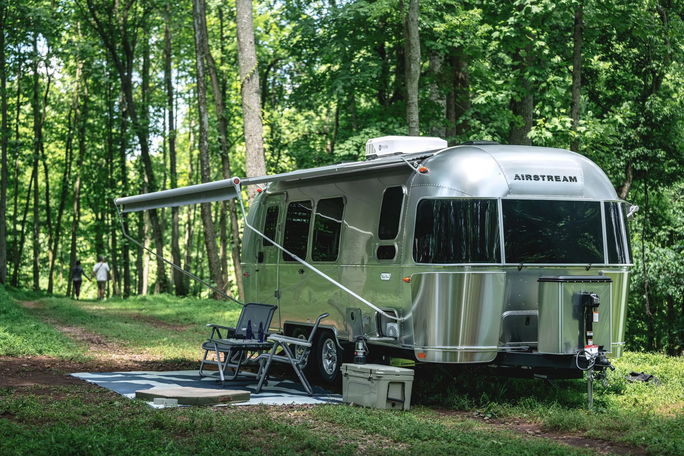 Airstream Flying Cloud with its awning out at a wooded campsite