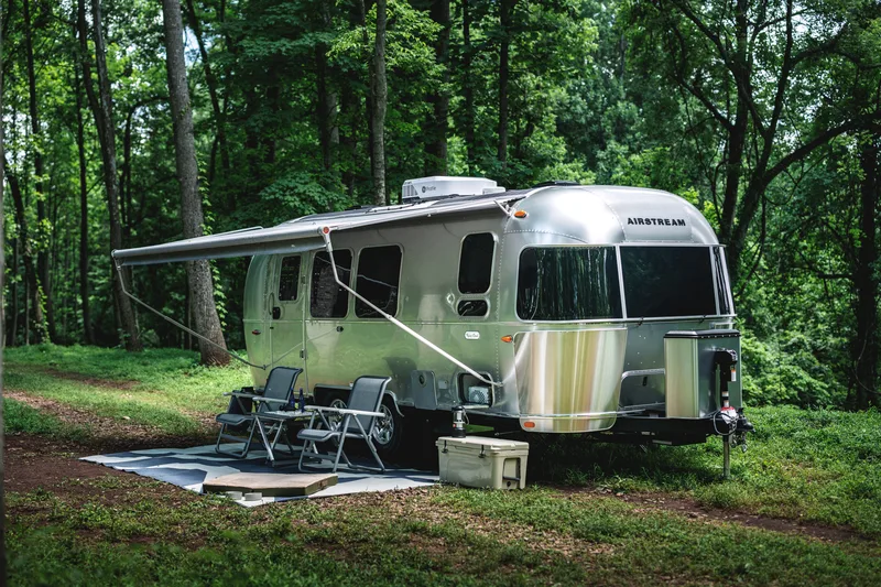 Airstream Flying Cloud set up at a wooded campsite