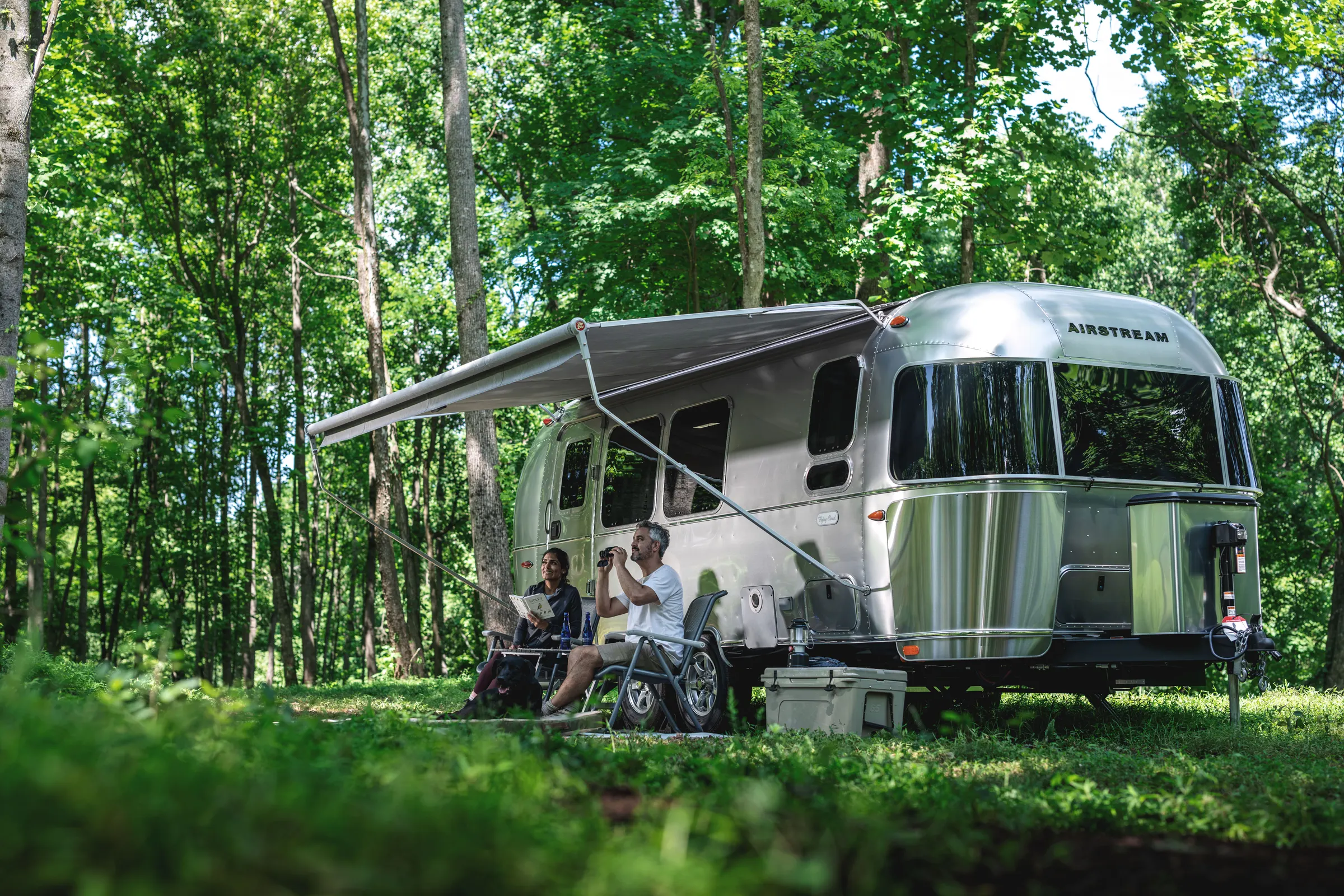 Airstream Flying Cloud with its awning out in a green forest
