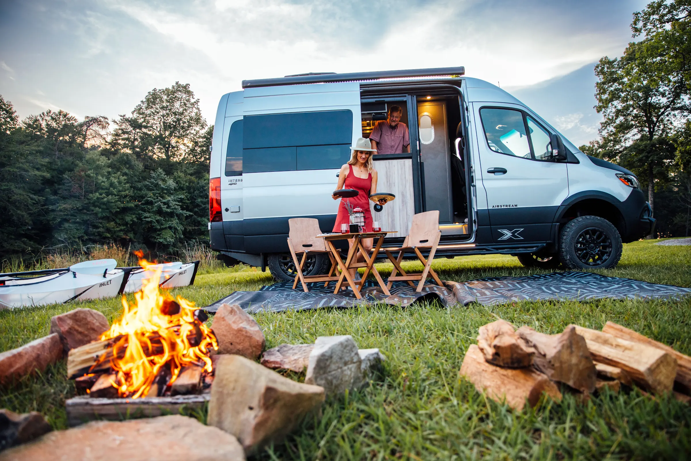 Campfire beside an Airstream Interstate touring coach at dusk