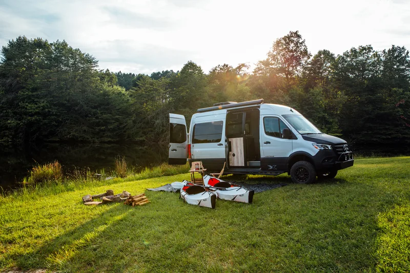 Friends at a campsite beside an Airstream Interstate